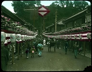 Crowd-filled street lined with banners and lanterns