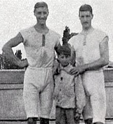 Photo de deux hommes en tenue de sport posant avec un jeune garçon.