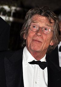 A grey-haired man in glasses, wearing a tuxedo