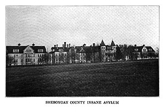 A long line of 3-story Victorian buildings with a central turreted gatehouse