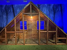 A wooden, triangular, hut-like structure.