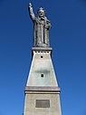 Statue en métal sur un socle en béton d'un homme qui lève le bras droit.