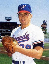 A man in a white baseball uniform with a blue cap