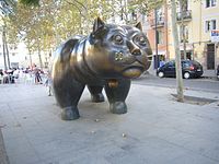 Tête d'un chat de bronze vu de face dans une rue commerçante