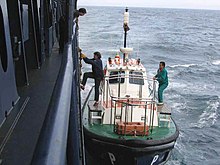 A pilot boarding a ship from a pilot boat while underway Harbour pilot boarding.jpg