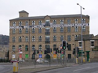 Five story building with many high windows stretching across the background with road and traffic light controlled junction in front