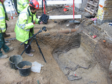 A photographer taking a record shot of a horse burial in a Roman ditch re-cut. A re-cut is a type of feature. Maggie and horse.PNG