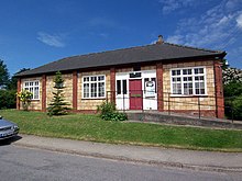 Parish Hall, a single story building with a hipped roof and tiled walls