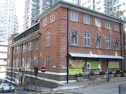 Upper elevation of three-storey red brick corner-building with flat roof