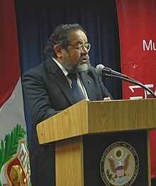 A man standing at a podium, reading from his notes as he speaks into the microphone