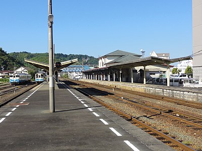 A view of the station platforms and tracks. A passing loop can be seen on the right, between the two platforms. Sidings can be seen branching to the left beyond the island platform.