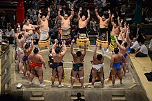 Sumo wrestlers form around the referee during the ring-entering ceremony. Aki basho dohyo-iri on Sept. 28 2014.jpg