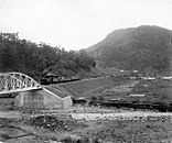 Zug der Padangbahn im Sawahlunto-Tal, im Hintergrund Berg mit Kohle-Lagerstätte