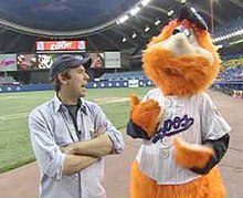 Youppi!, a big, bright orange furry mascot, interacts with a fan inside Montreal Olympic Stadium.