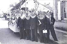 Photographie en noir et blanc montrant un groupe de jeunes hommes enrubannés.