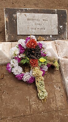 Photograph of the grave of Titina Silá, with a wreath of flowers placed on it