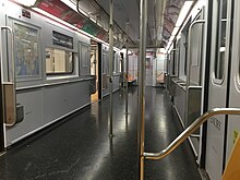 The interior of a R62A subway car used on the 42nd Street Shuttle, which was retrofitted to increase capacity. Almost all of the seats have been removed, original lighting still present.