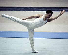 Un homme réalisant une figure de gymnastique sur un tapis.