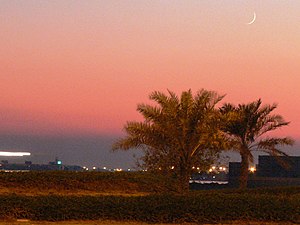 A crecent moon can be seen over palm trees at ...