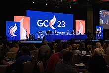 Group of people in a business meeting. GC23 logo on digital background blue screen.