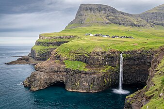 Voda z vodopádu Múlafossur na Faerských ostrovech padá přímo do moře