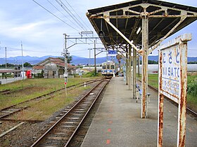 Photo couleur d'un quai de gare avec un train arrivant