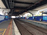 Southbound view from Platform 1, with the station underneath an incomplete elevated rail viaduct, in May 2022.