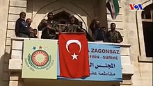 Turkish soldiers and TFSA fighters at the building in Afrin that had hosted the PYD-led government of the region, 18 March 2018 Turkish Army Captured Afrin 01.jpg