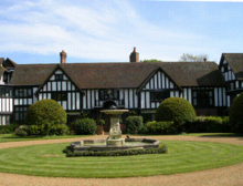 This simple cottage, Ascott House in Buckinghamshire designed c. 1876 by George Devey, is an early example of Tudorbethan influence Ascott House Front.png