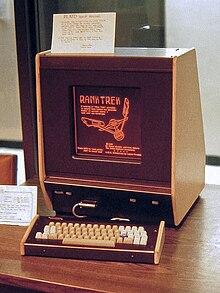 A PLATO V terminal in 1981, displaying RankTrek application, one of the first to combine simultaneous local microprocessor-based computing with remote mainframe computing. The monochromatic plasma display's characteristic orange glow is illustrated. Infrared sensors mounted around the display watch for a user's touch screen input. Platovterm1981.jpg