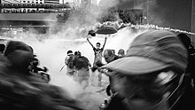 The "Umbrella Man" photo as police dispersed peaceful demonstrators with tear gas. 2014 Hong Kong Umbrella Revolution as Police Attacked Peaceful Demonstrators with Tear Gas Xiang Gang Zha Da Ge Ming Zhi He Ping Kang Yi De Xiang Gang Ren Min Yi Yu San Dui Kang Fa She Cui Lei Dan De Gang Jing .jpg