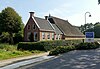 Kop-hals-rompboerderij met voorhuis met zesruitsvensters en stichtingssteen tussen twee topgevels waarop schoorstenen met borden