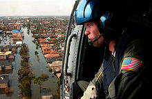 A U.S. coast guardsman searches for survivors in New Orleans in the Katrina aftermath. New Orleans Survivor Flyover.jpg