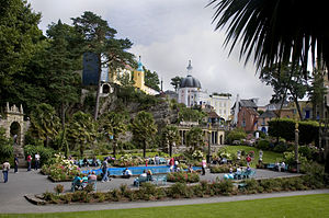 Colourful buildings in contrasting architectural styles surround a palm tree-lined paddling pool.