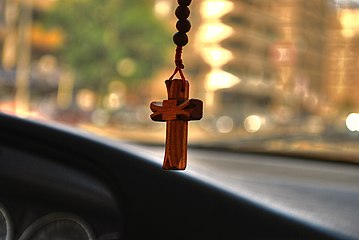 A rosary hanging from the rear-view mirror of a car