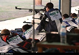 Photograph of shooters in canvas jackets: one is kneeling, the others lie on their fronts.