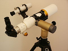 A refracting telescope (with finderscope and accessories) on a small alt-azimuth mount.
