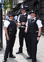 Met Police officers on the streets of Soho. Since 1863, the custodian helmet (middle) has been worn by male police constables and sergeants while on foot patrol. Very friendly MPS officers in London.jpg