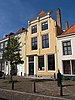 Huis met geverfde lijstgevel, aan de hoeken ingezwenkt. Lijstfries gebeeldhouwde cartouches en gebeeldhouwde consoles. Staafankers. Empire vensters met middenstijl. Voordeuromlijsting met snijwerk en bovenlicht. Geverfd jaartal. Stoep en hardstenen paal