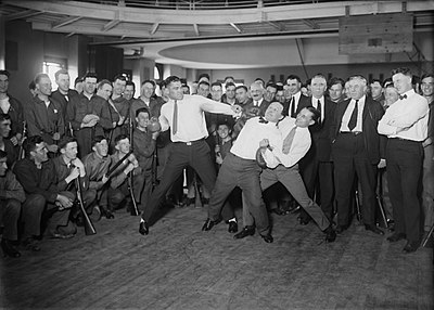 Heavyweight boxing champion Jack Dempsey mock punching Harry Houdini, who is held back back by lightweight boxing champion Benny Leonard.