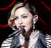 Мадонна в блестящем топе поет.
