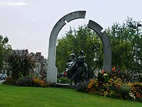 Cœur fleuri du rond-point, avec une sculpture représentant deux personnes surplombées par une arche en deux parties.