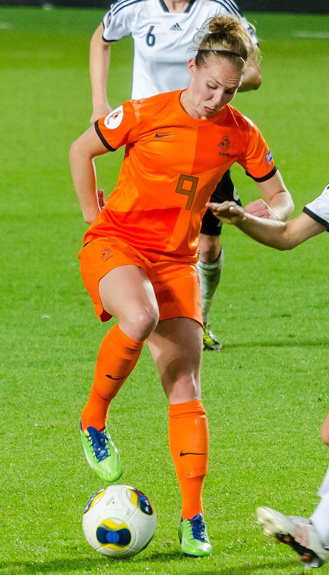 Photo of Dutch international footballer Manon Melis in orange football kit with a ball
