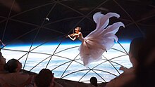 Violinist with fancy dress floating, with audiences watching