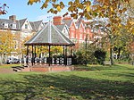 a bandstand in a park (temple gardens), with houses in the background