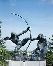 Die Skulptur des Bogenschützen von vorne, gegen blauen Himmel fotografiert