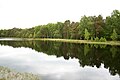 Wasserfläche mit Infotafel im Hintergrund am Ufer