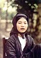 A northern Vietnamese girl with black teeth sitting on a chair.