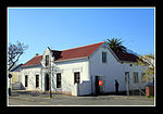 This U-shaped building has a feature peculiar to Hottentots Holland; namely a front gable with small distinctive 'thumb wings' reduced to the width of the edge- mould only. The Police Station, originally a dwelling-house, probably dates from between 1835 Architectural style: Cape Gabled. Type of site: Police Station. Current use: Police station.