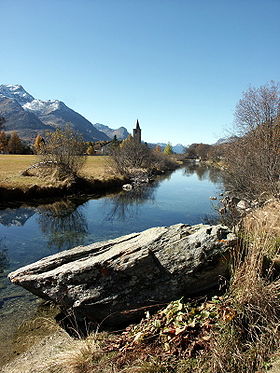 Inn, im Hintergrund die Kirche von Segl Baselgia